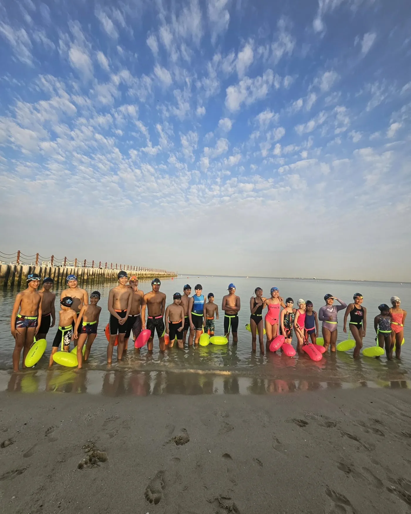 Water Warriors swimmers standing together in the shallows with swim buoys