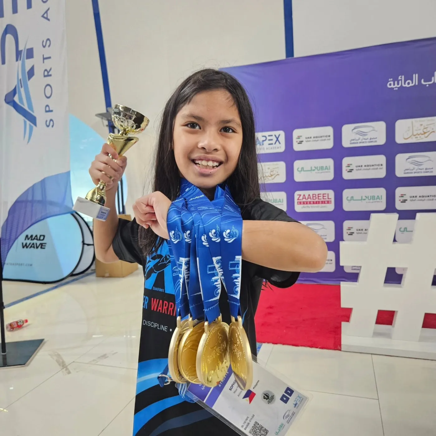 A Water Warriors swimmer celebrating with a trophy and medals at DIAC