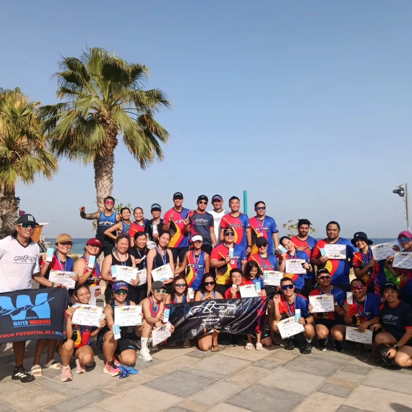 FiT community group celebrating with Water Warriors and Filipino International Triathletes banners