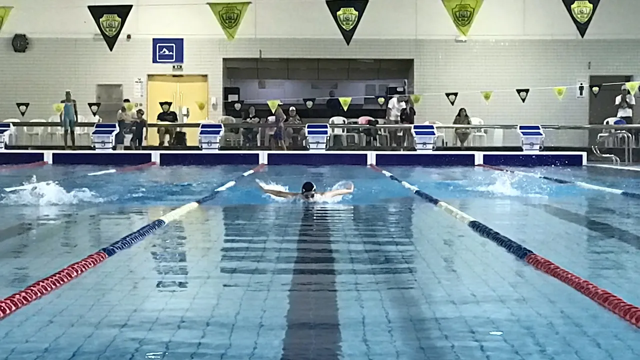 A swimmer practising butterfly in the centre lane